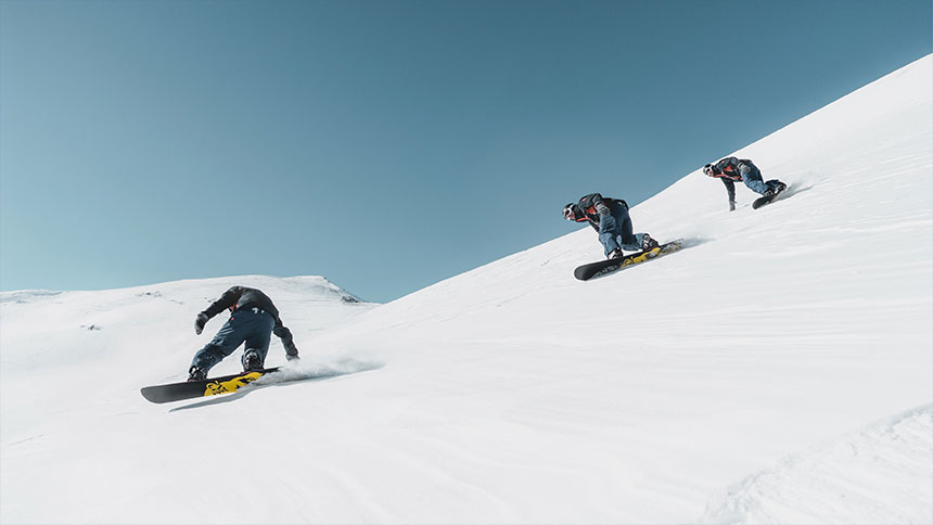des snowboarders descendent une piste