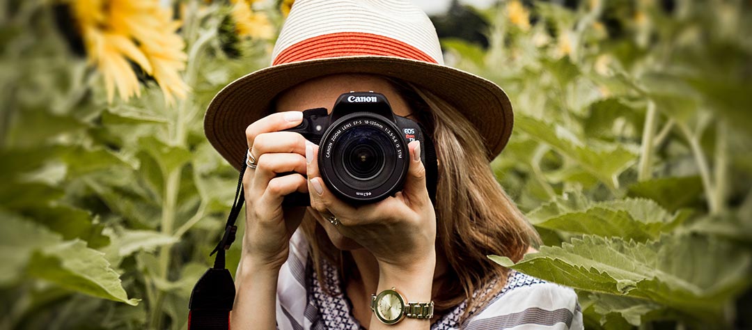 Femme photographe avec un reflex sur fond de plantes
