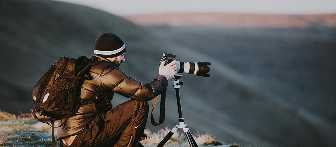 photographe en montagne avec un appareil photo reflex professionnel
