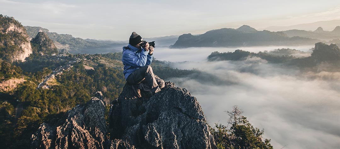 Photographe sur un rocher en montagne en tenue outdoor