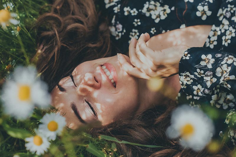 photo femme allongée dans l'herbe et fleurs