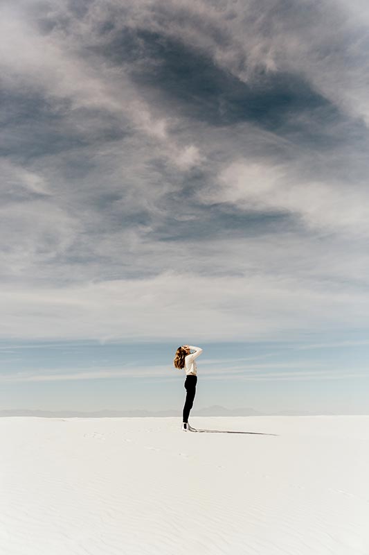 Femme debout au loin sur le sable dans un désert