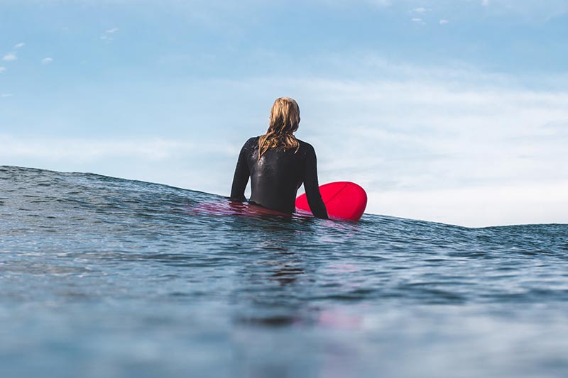 femme qui surf planche de surf rouge