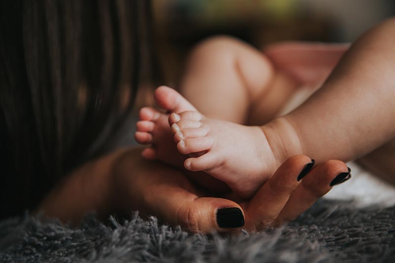 pied de bébé dans la main de sa maman